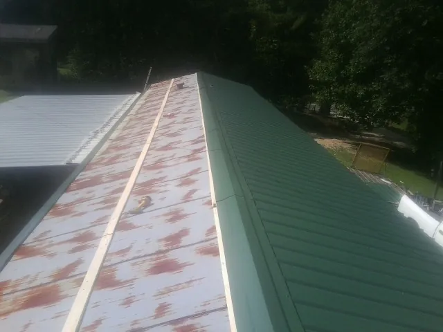 Old rusted panels beside newly installed green metal roofing — Wind Damage Roof Repair by Roofing Brothers in Hilliard