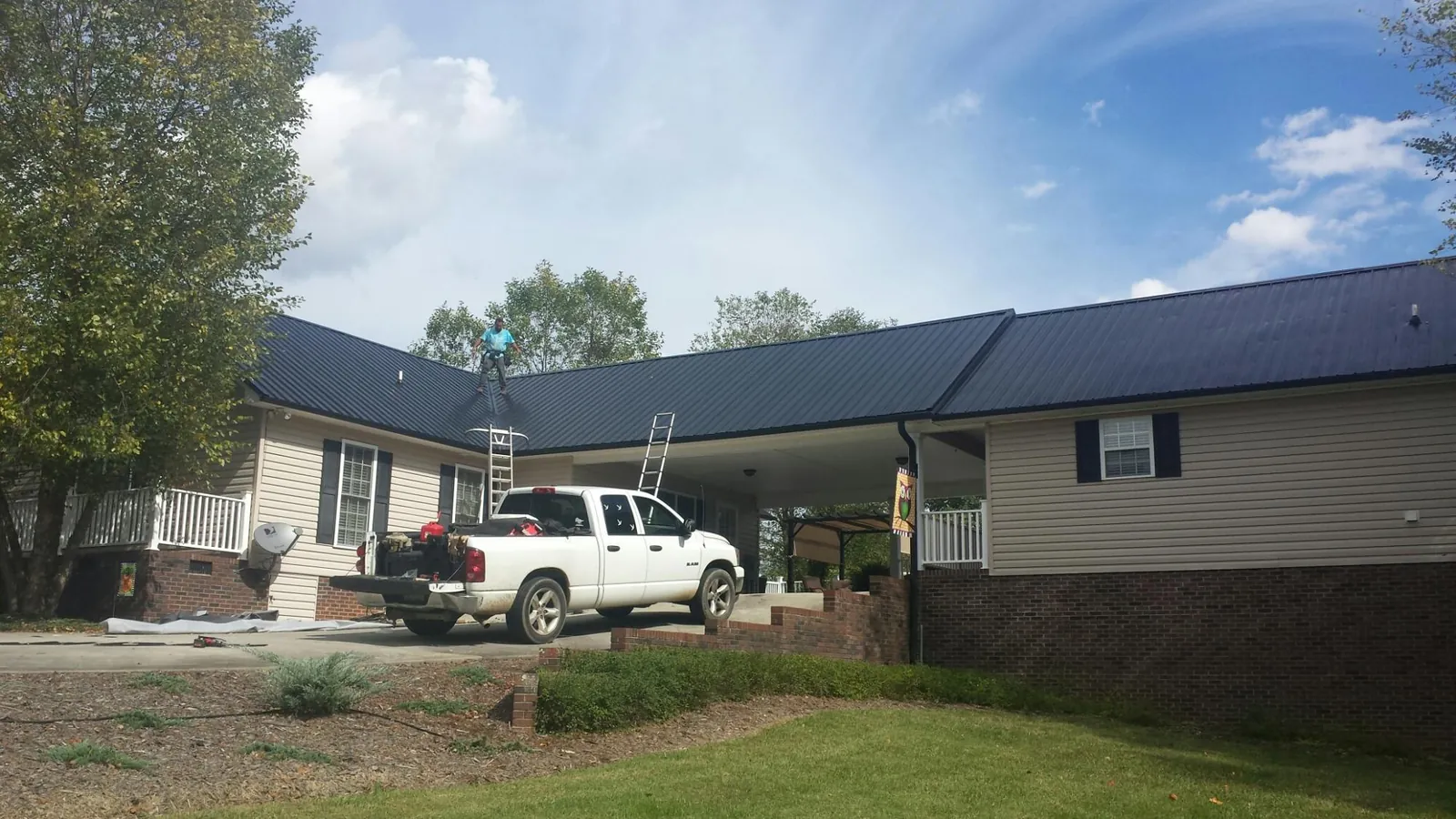 Black metal roof over a home and attached breezeway with ladders set in Hilliard