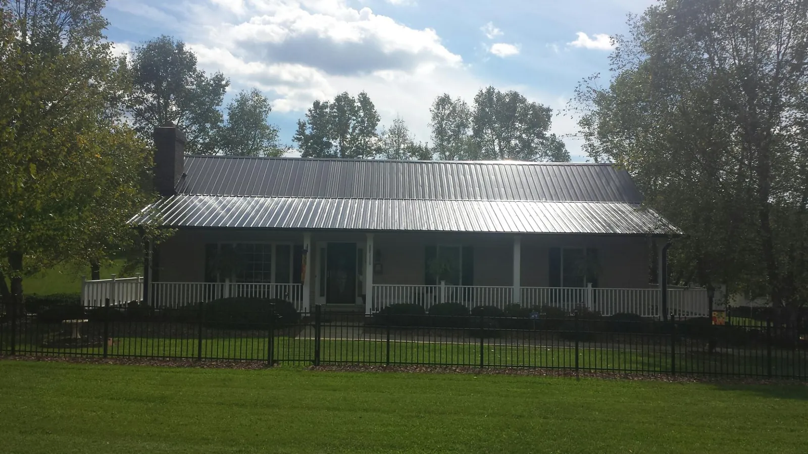 Gray metal roof on a brick ranch with a full width front porch — Gutter Guard Installation work by our crew in Hilliard
