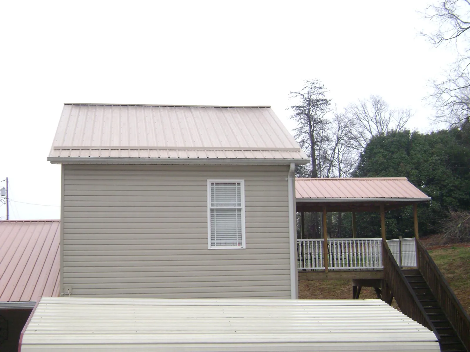 Tan metal roofs on a two story addition and attached porch, from a Roof Replacement job in Hilliard